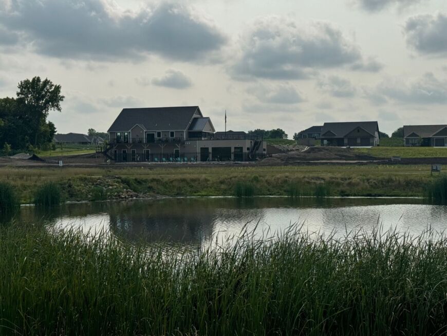 Siesta Hills clubhouse and pond view in Mankato Minnesota with homes and scenic water reflection